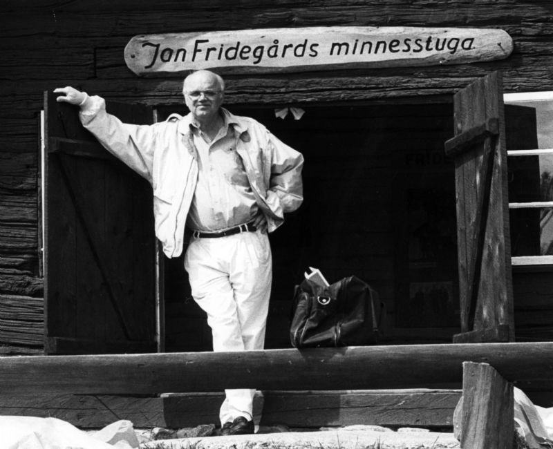 Hasse Eson, initiativtagare till Jan Fridegårdsällskapet och vice ordförande under många år, i dörröppningen till minnesstugan i Gåde. Foto: Enköpings Posten